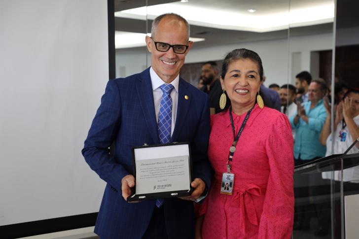 Foto colorida do presidente desembargador marcus augusto losada e a diretora geral durante a entrega da placa celebrativa da gestão 2022-2024.