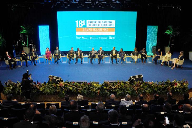 Foto colorida tirada durante a premiação. Os indicados estão no palco sentados durante uma roda de conversa.