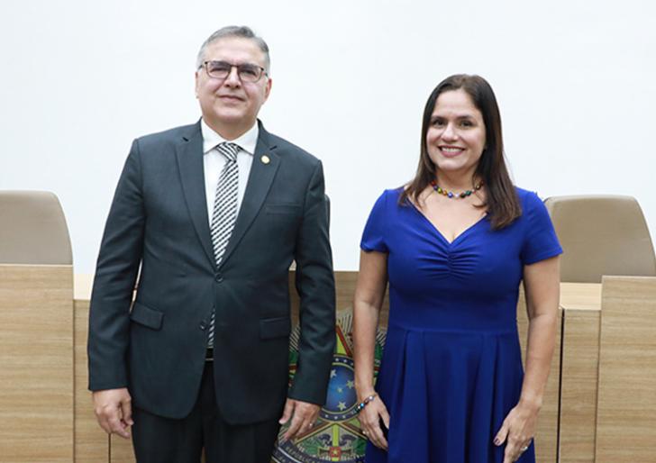 #ParaTodosVerem: Fotografia em ambiente fechado que reúne lado a lado, um homem branco de terno escuro e uma mulher branca de vestido azul