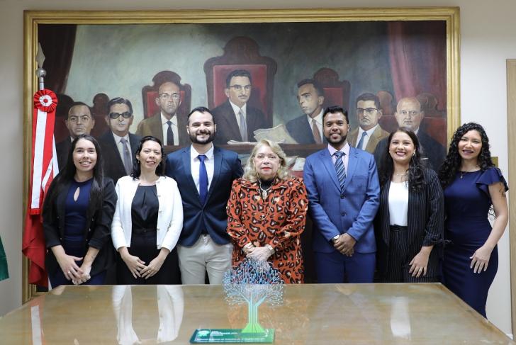 Foto colorida. Os seis novos servidores posam lado a lado com a presidente do TRT-8, na antessada da Presidência.