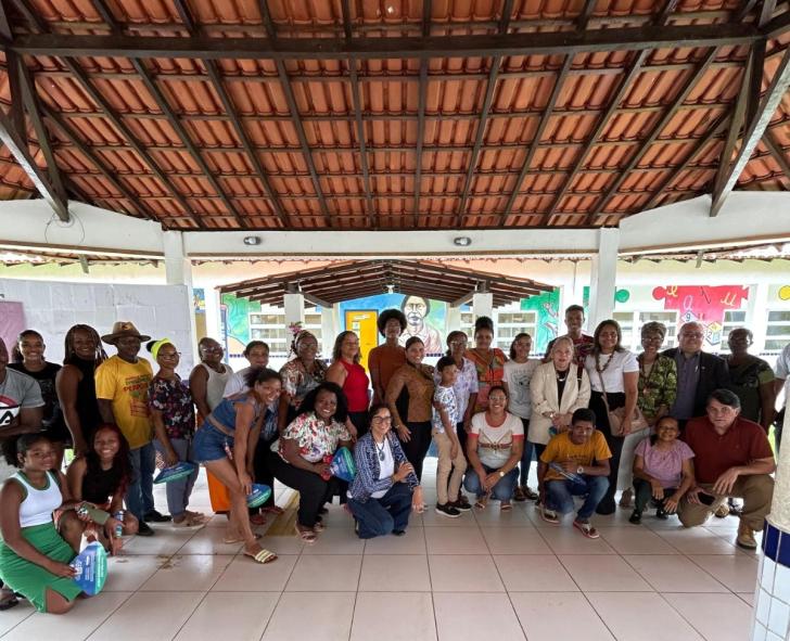 Foto colorida de um grande grupo de moradores de curiaú junto a magistrados do TRT8 em visita a uma escola local