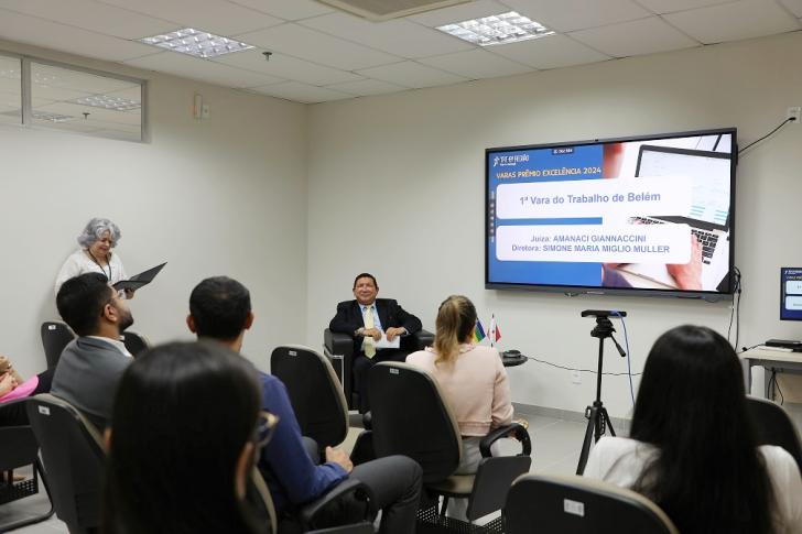 Foto colorida da sala de conferências da EJUD. À frente, sentado, o corregedor regional. Diante dele, magistrados e servidores acompanham as falas de abertura do ano correicional.