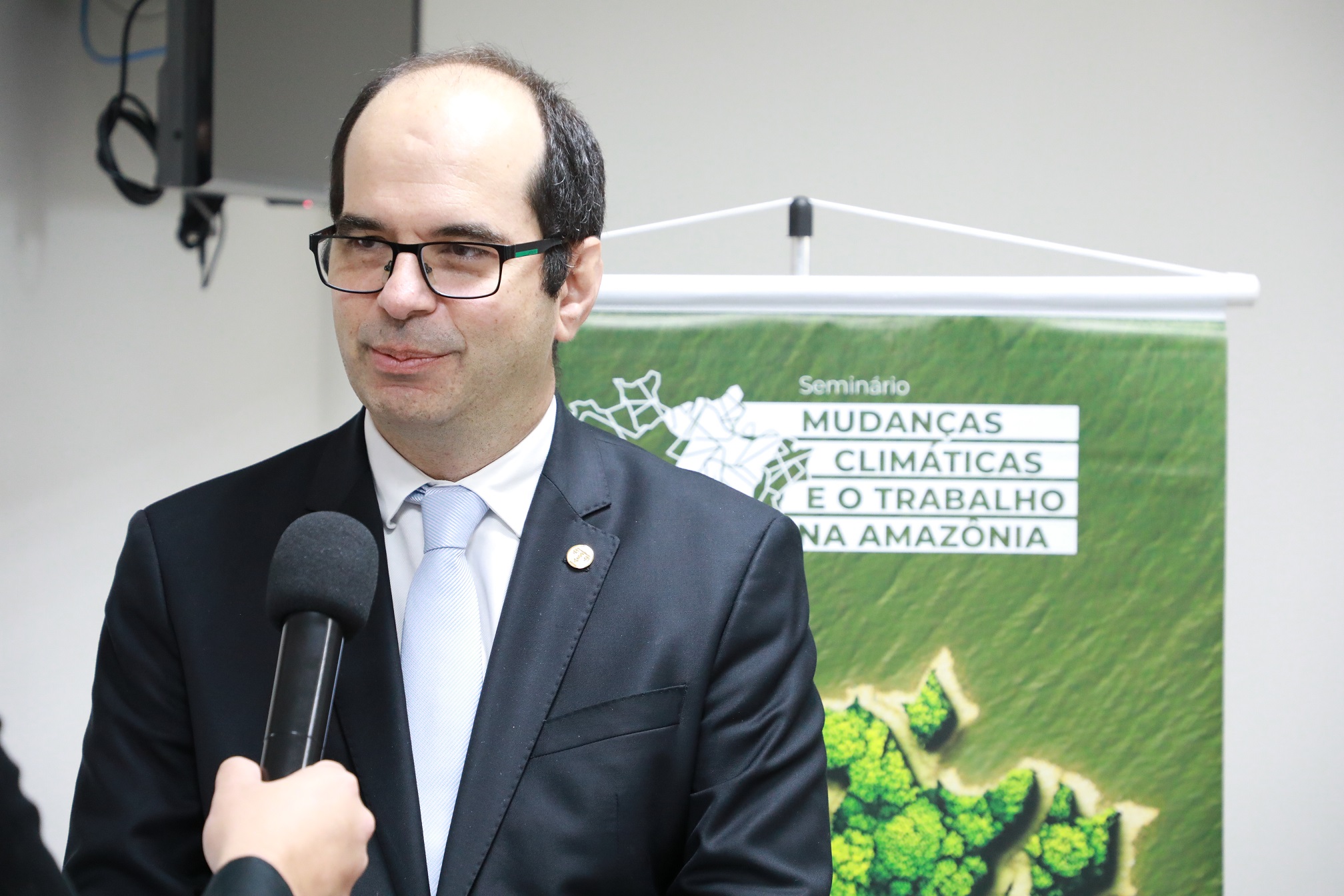 foto colorida do ministro alberto balazeiro. ao fundo, banner do seminário mudanças climáticas e o trabalho na amazônia.