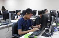 Descrição de imagem: Fotografia contendo algumas crianças e adolescentes mexendo em computadores.