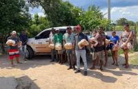 Fotografia com onze pessoas de pé segurando cestas básicas. 