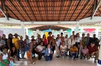 Foto colorida de um grande grupo de moradores de curiaú junto a magistrados do TRT8 em visita a uma escola local